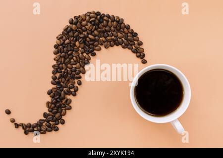 Fondo piatto beige con tazza di caffè in ceramica bianca, caffè tostato in grani forma di vapore dal caffè caldo. Idea e composizione con chicchi di caffè Foto Stock