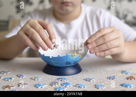 Teenager boy raccoglie puzzle da un Globe Foto Stock