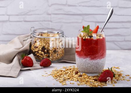 Sana chia, cocco, budino di fragole con granola fatta in casa su tavolo di legno bianco Foto Stock