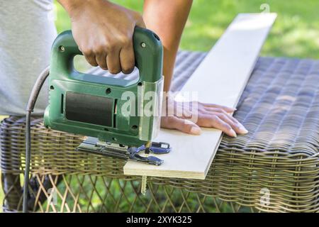 Donna segare tavolato in legno con elettrico seghetto alternativo Foto Stock