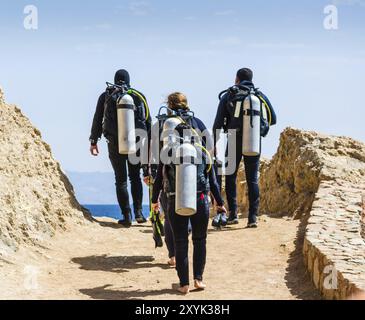 I subacquei con l'attrezzatura per le immersioni subacquee vanno al mare sul cielo con le nuvole in Egitto Dahab Foto Stock