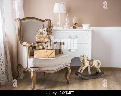 Parte di una genitorialità e baby room con poltrona e cassettiera Foto Stock