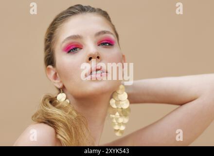 Modello di bella ragazza con manicure rosso sulle unghie. Moda bright make up e cosmetici. Indossando grande golden shine orecchini gioielli Foto Stock