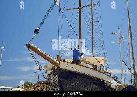 Un uomo ripara la barca a vela in legno all'albero sotto un cielo blu, Patmos Marine, cantiere navale, Diakofti, Patmos, Dodecaneso, Isole greche, Grecia, Euro Foto Stock