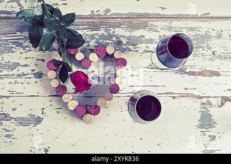 Due bicchieri di vino rosso un cuore con sughero e una rosa rossa in stile vintage Foto Stock