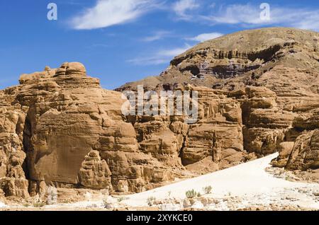 Alte montagne rocciose contro il cielo blu e nuvole bianche nel deserto in Egitto, Dahab, Sinai meridionale Foto Stock