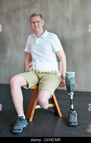 Uomo, ritratto e amputato sorridono con protesi gamba in palestra, seduta con un arto residuo per il montaggio. Allenamento, fisioterapia nel benessere o nella persona maschile Foto Stock
