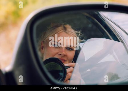 Riflesso di una donna fotografa nello specchio laterale Foto Stock