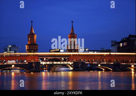 Ponte oberbaumbruecke di Berlino con passaggio notturno del treno arancione della metropolitana. colori vivaci ed esposizione prolungata Foto Stock