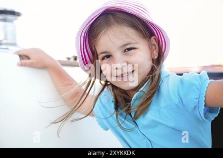 Bambina sognante mentre si fa un viaggio in barca, godendo di mare calmo, guardando la macchina fotografica con espressione felice. Viaggio in nave Foto Stock