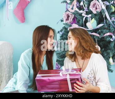 Ritratto di una madre con la figlia teenager essendo vicino e abbracciando a casa vicino l'albero di Natale di essere felice e gioiosa Foto Stock