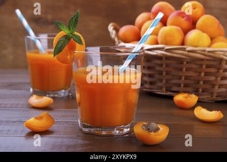 Primo piano di succo fresco con albicocche in un cestello di vimini su sfondo di legno Foto Stock
