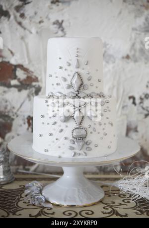 Bianco torta di nozze con decorazioni di argento sul tavolo Foto Stock