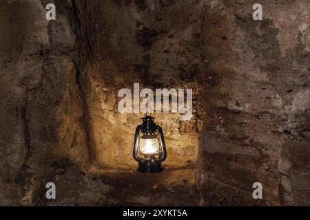 Una lampada a paraffina brucia di notte su un piedistallo in un vecchio castello in rovina su arenarie Foto Stock