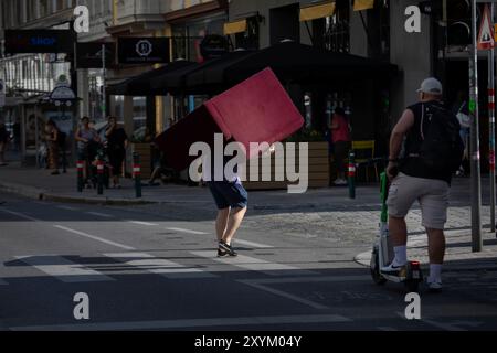 Vienna, Austria. 29 agosto 2024. AUSTRIA; VIENNA; 20240829; Un uomo porta un piccolo divano dall'altra parte della strada a Vienna il 29 agosto 2024. // Österreich; WIEN; 20240829; Ein Mann trägt ein kleines Sofa über eine Strasse in Wien am 29. Agosto 2024. - 20240829 PD23360 credito: APA-PictureDesk/Alamy Live News Foto Stock