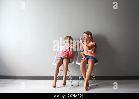 Felice ragazza in una discussione con il suo piccolo. Decisione problemi tra sorelle concetto. Di mano in mano Foto Stock