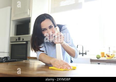 Brunette donna con rag e la bottiglia spray di pulizia contatore di legno-top Foto Stock