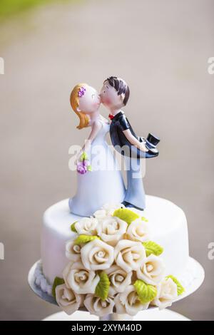 Torta nuziale con una piccola statuetta di coppia nuziale su un'etagera Foto Stock