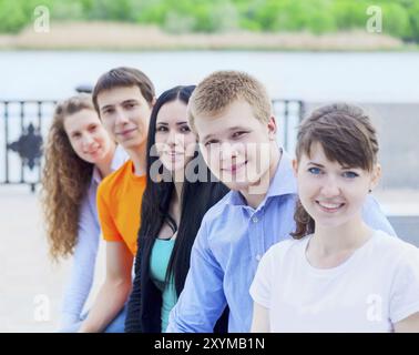 Un gruppo di ragazzi sorridenti seduti all'aperto. Il concetto di amicizia Foto Stock