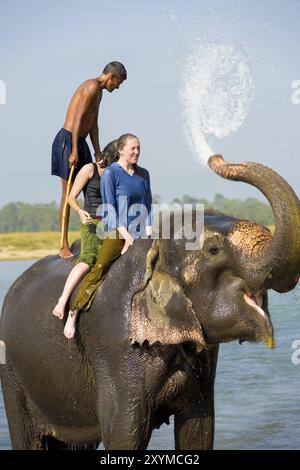 Chitwan, Nepal, 5 dicembre 2007: Due turisti femminili che si bagnano con l'acqua del tronco durante un giro in elefante nel fiume al Parco Nazionale di Chitwan, Asi Foto Stock