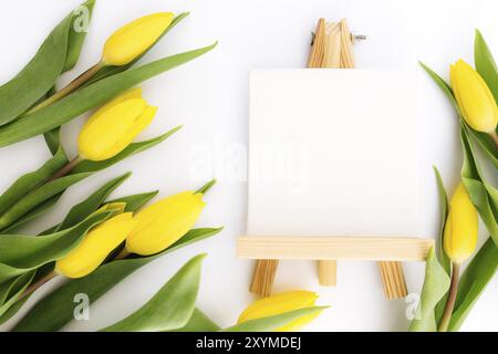 Piatto con fiori di tulipano gialli e cornice vuota su sfondo bianco. Biglietto d'auguri per Pasqua, Festa delle madri, Giornata internazionale delle donne Foto Stock