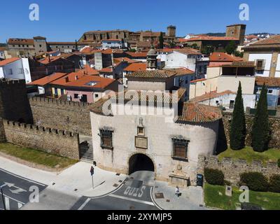 Città storica con un cancello d'ingresso fortificato e una cinta muraria ben conservata, circondata da vecchi edifici con tetti rossi, vista aerea, Puerta de Trujil Foto Stock