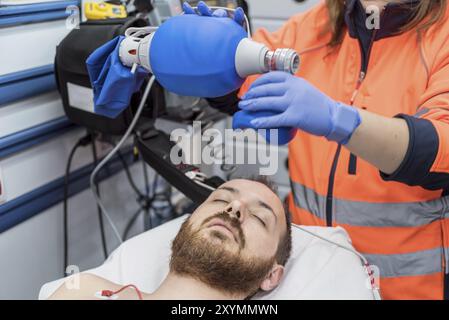 Covid-19 insufficienza respiratoria. Medico d'urgenza usando maschera Ambu sacco su un paziente con polmonite a causa di infezione da Coronavirus, per ventilazione artificiale Foto Stock