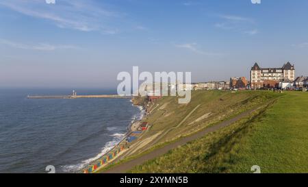 Whitby, North Yorkshire, Inghilterra, Regno Unito, 8 maggio, 2016: vista sullo skyline di Whitby, le capanne sulla spiaggia e il molo, vista dalla North Promenade Foto Stock