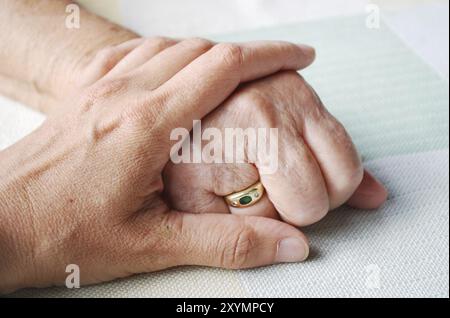 Mano di un medico o di un infermiere che tiene per mano una donna anziana Foto Stock