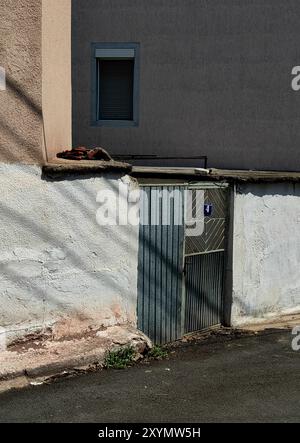 In Ombre e luce.: Telaio porta in metallo con numero quattro, con piastra blu. Cornice della finestra sulla parete. Foto Stock