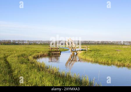 Piccolo ponte in legno aperto per biciclette sul canale olandese, Olanda Foto Stock