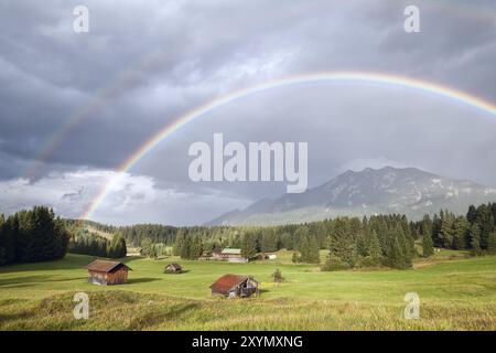 Arcobaleno colorato su prati alpini con capanne di legno, Baviera, Germania, Europa Foto Stock