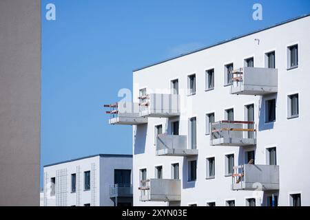 Berlino, Germania. 29 agosto 2024. Foto simbolica sul tema della costruzione di nuovi appartamenti. Quartiere urbano di Buckower Felder nella periferia sud di Berlino. Circa 900 appartamenti sono stati costruiti su un sito di circa 16 ettari. Un ombrellone si trova sul balcone di un nuovo appartamento che è già stato occupato. Vista dei balconi in costruzione. Berlino, 29 agosto 2024. Credito: dpa/Alamy Live News Foto Stock