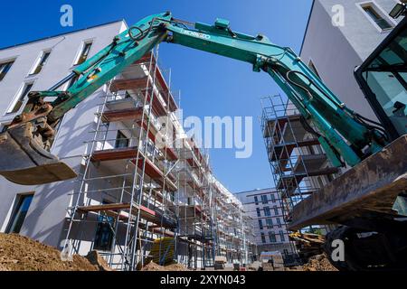 Berlino, Germania. 29 agosto 2024. Foto simbolica sul tema della costruzione di nuovi appartamenti. Quartiere urbano di Buckower Felder nella periferia sud di Berlino. Circa 900 appartamenti sono stati costruiti su un sito di circa 16 ettari. Un escavatore si trova di fronte agli appartamenti in affitto quasi finiti. Berlino, 29 agosto 2024. Credito: dpa/Alamy Live News Foto Stock