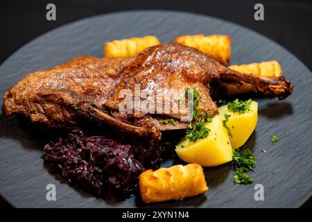 Mezza anatra con patate e crocchette su un piatto Foto Stock