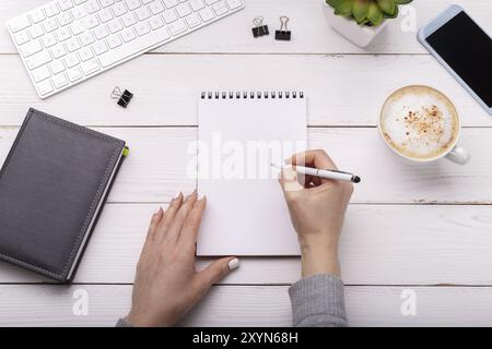 Mani femminili con la penna sul desktop, blogger o business donna tenendo un tablet. Appartamento laico, vista aerea Foto Stock