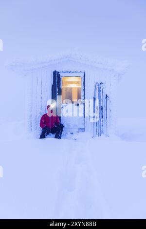 Sciatore che riposa di fronte a una capanna, riserva naturale di Dundret, Gaellivare, Norrbotten, Lapponia, Svezia, novembre 2016, Europa Foto Stock