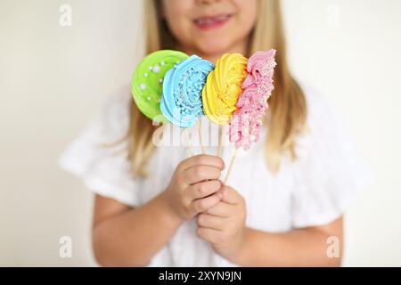 Carino bambina con caramelle pop su sfondo bianco Foto Stock