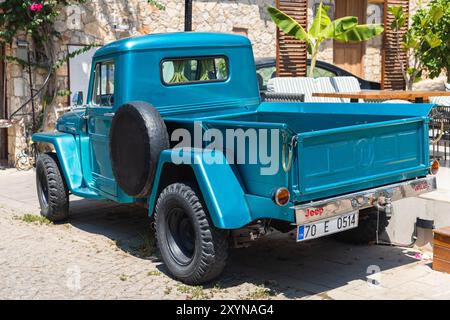 Kalkan, Turchia - 15 agosto 2024: Punti di prelievo blu parcheggiano sulla strada in una giornata di sole, vista posteriore. Willys Jeep Truck è un camion prodotto da Willys-Over Foto Stock