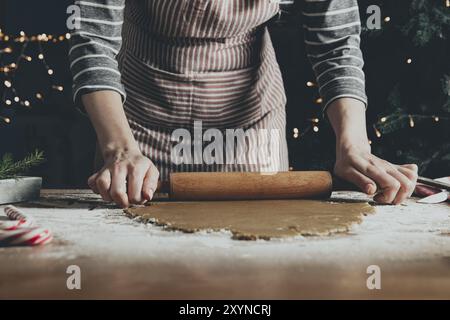 Buon Natale, Felice Anno Nuovo. Cottura del pan di zenzero, torta o strudel. Una giovane donna o una madre stenderà l'impasto con una sedia a dondolo per il ext Foto Stock