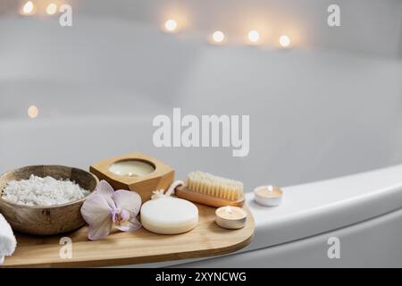 Preparazione per il trattamento termale dell'hotel, procedura per il bagno domestico. Lavabo bianco in bagno, accessori su vassoio candele brucianti, sapone, spazzola per piedi, asciugamano, Foto Stock