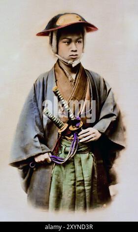 Giovane uomo in abito e armatura Samurai 1890 fotografo Unkown, foto giapponese in bianco e nero colorato a mano Giappone fine XIX - inizio del XX secolo fotografia di albume d'epoca ( storia storica ) riproduzione digitale migliorata . Foto Stock