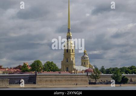 La Cattedrale di Pietro e Paolo sorge con la sua suggestiva guglia dorata sotto un cielo nuvoloso su una riva del fiume, san pietroburgo, Mar baltico, russia Foto Stock