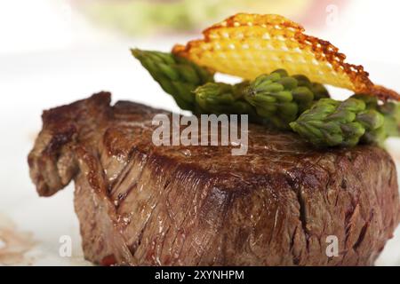 Primo piano di una bistecca di manzo con asparagi verdi su sfondo bianco Foto Stock