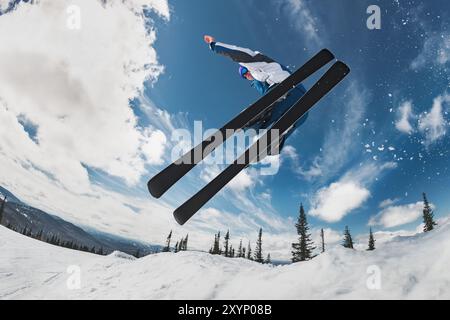 Sciatore veloce senza bastoni da sci salta contro il cielo blu Foto Stock