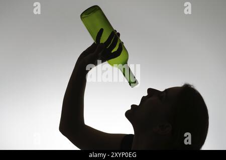 Bevande alcoliche donna di silhouette con un vuoto di bottiglia di vino Foto Stock