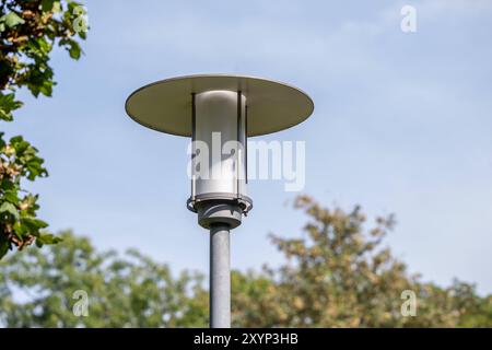 Moderne Straßenlaterne im Grünen , Deutschland, 30.08.2024, Eine moderne Straßenlaterne steht im Freien, umgeben von Grünen Bäumen und einem klaren blauen Himmel. DAS Design der Laterne ist schlicht und funktional, passend zur urbanen Umgebung. *** Lampada da strada moderna in campagna, Germania, 30 08 2024, Una moderna lampada da strada si erge all'aperto, circondata da alberi verdi e un cielo azzurro limpido il design della lanterna è semplice e funzionale, in armonia con l'ambiente urbano Foto Stock