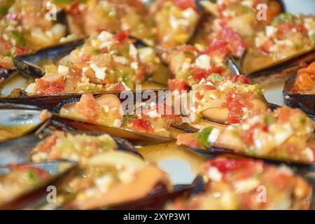 Primo piano sui vivaci dettagli delle cozze serviti con un colorato condimento di vinaigrette. Ogni guscio di cozze è abbondantemente ricoperto con un mix di t tritate Foto Stock