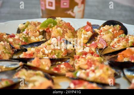 Primo piano sui vivaci dettagli delle cozze serviti con un colorato condimento di vinaigrette. Ogni guscio di cozze è abbondantemente ricoperto con un mix di t tritate Foto Stock