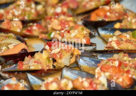 Primo piano sui vivaci dettagli delle cozze serviti con un colorato condimento di vinaigrette. Ogni guscio di cozze è abbondantemente ricoperto con un mix di t tritate Foto Stock